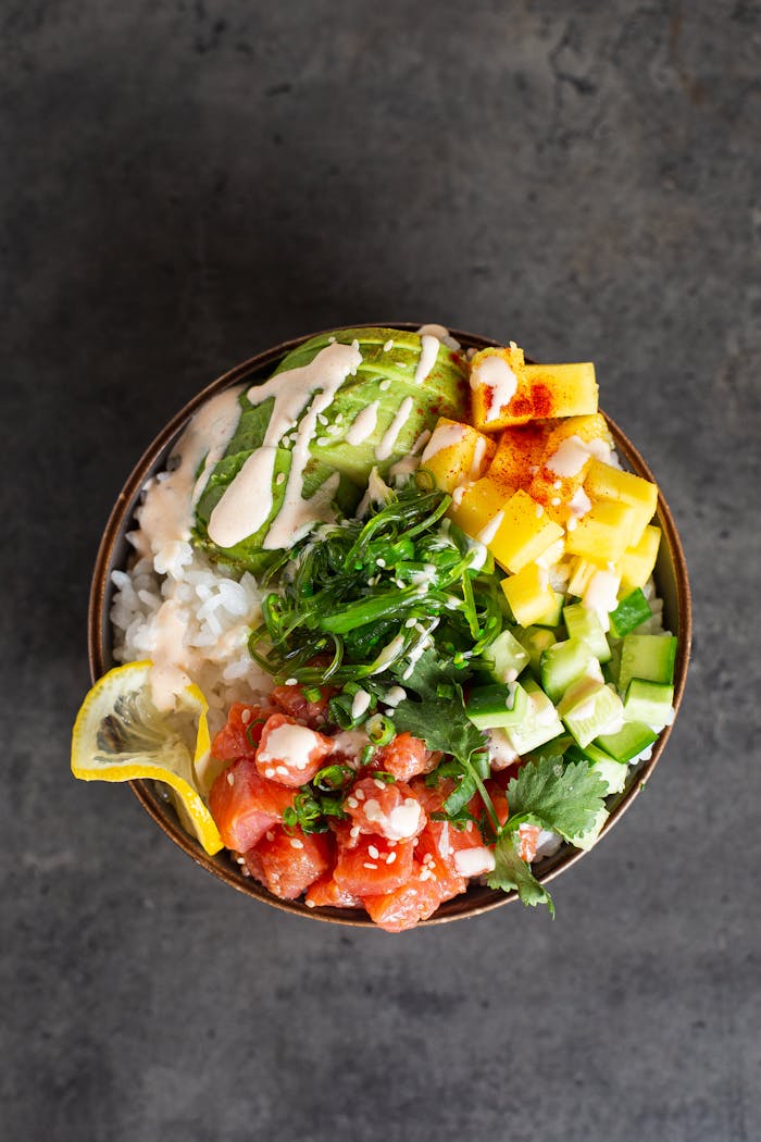 our-story Top view of a vibrant Hawaiian poke bowl featuring fresh fish, avocado, mango, and rice.